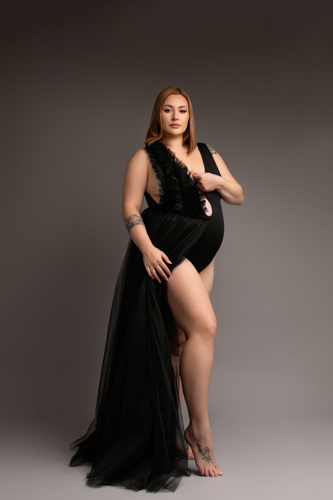 sesja ciązowa w studio, kobieta w body na szarym tle