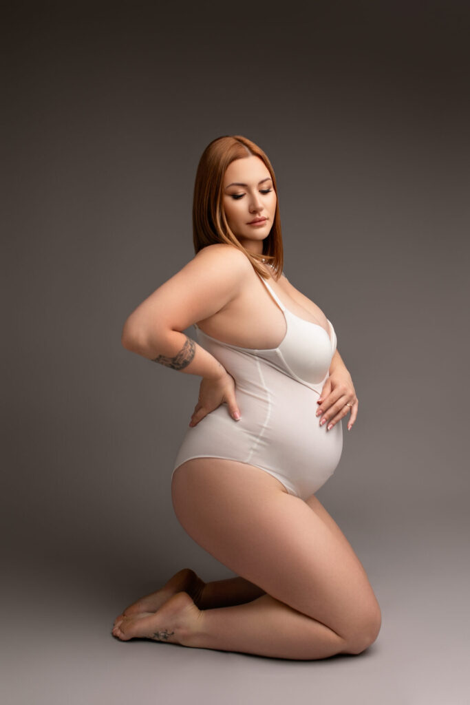 sesja ciążowa w studio, kobieta w białym body, zdjęcie sensualne